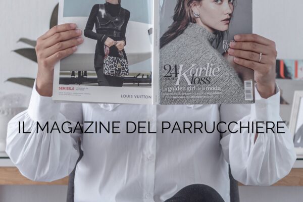 Donna in camicia bianca legge una rivista di moda con la copertina aperta, con il testo sovrapposto "Il Magazine del Parrucchiere".