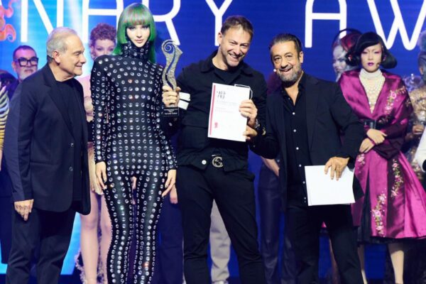 Matteo Susini premiato sul palco del Visionary Award 2024, affiancato da una modella con i capelli verde lime e altri partecipanti, mentre riceve il trofeo per la categoria Cut and Color.