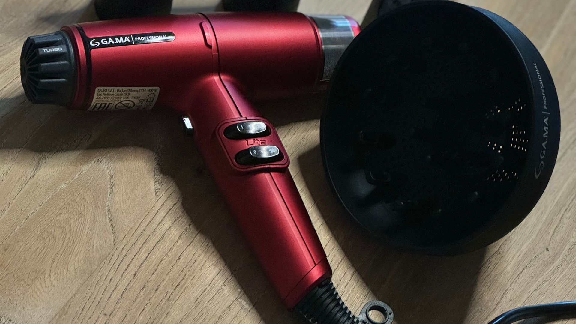 Asciugacapelli professionale Gama IQ Lite Max in color rosso, affiancato da due concentratori e un diffusore. Il design compatto e leggero, insieme agli accessori professionali, lo rende ideale per una varietà di styling in salone.