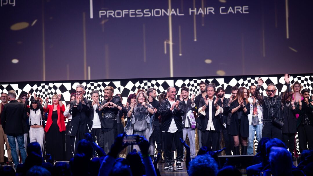 Hairstylist e membri del team SCREEN e tagliatiXilsuccesso sul palco del Palariccione durante la Two Days Experience 2024, celebrando il successo dell'evento con applausi ed entusiasmo.