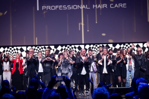 Hairstylist e membri del team SCREEN e tagliatiXilsuccesso sul palco del Palariccione durante la Two Days Experience 2024, celebrando il successo dell'evento con applausi ed entusiasmo.