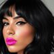 Donna con capelli neri a caschetto ondulato, frangia leggera e trucco Hyper-Feminine Y2K con labbra fucsia e eyeliner grafico.