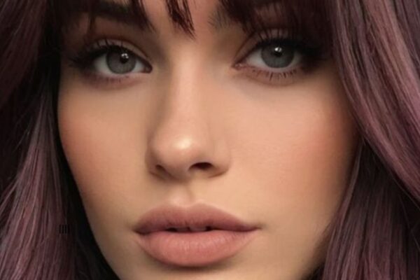 Donna con capelli color Cherry Cola, sfumature rosso ciliegia e marrone, look sofisticato e trendy.