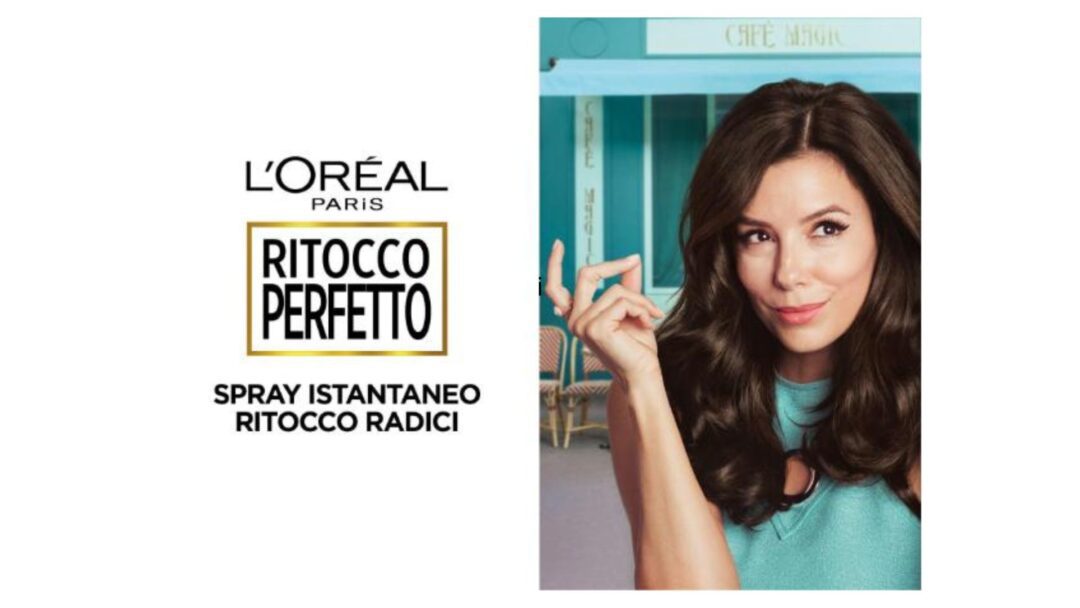 Donna con capelli scuri e lucenti tiene in mano uno spray L'Oréal Paris Ritocco Perfetto, con uno sguardo sicuro e soddisfatto.