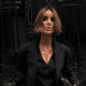 Donna con caschetto corto texturizzato e riga centrale, indossa un tailleur nero oversize con camicia sbottonata, sfoggiando un look sofisticato e moderno.