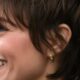 Donna over 40 sorridente con taglio di capelli pixie cut morbido e ciuffo laterale.