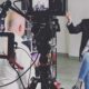 Intervista in studio con esperto del settore beauty davanti a telecamere e scaffali di prodotti cosmetici.