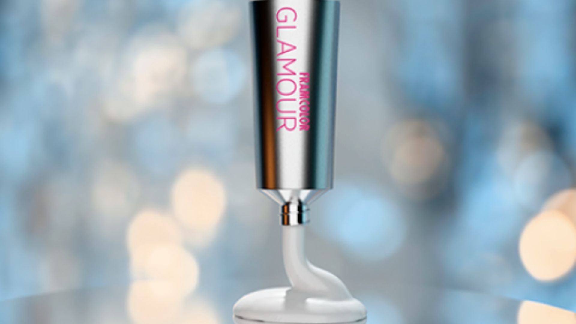 Tubo di colore professionale Framcolor Glamour di Framesi, in metallo satinato, con prodotto bianco in uscita, su sfondo sfocato blu