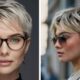 Due donne con tagli pixie moderni e capelli biondo freddo, una con occhiali da vista e una con occhiali da sole, mostrano due varianti eleganti del corto femminile.
