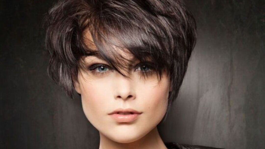 Donna con taglio corto scalato e frangia a tendina, stile moderno e voluminoso, ideale per un cambio look estate 2025
