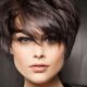 Donna con taglio corto scalato e frangia a tendina, stile moderno e voluminoso, ideale per un cambio look estate 2025