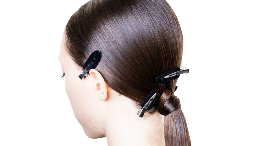 Capelli lisci e lucidi raccolti in una coda bassa con clip nere da backstage