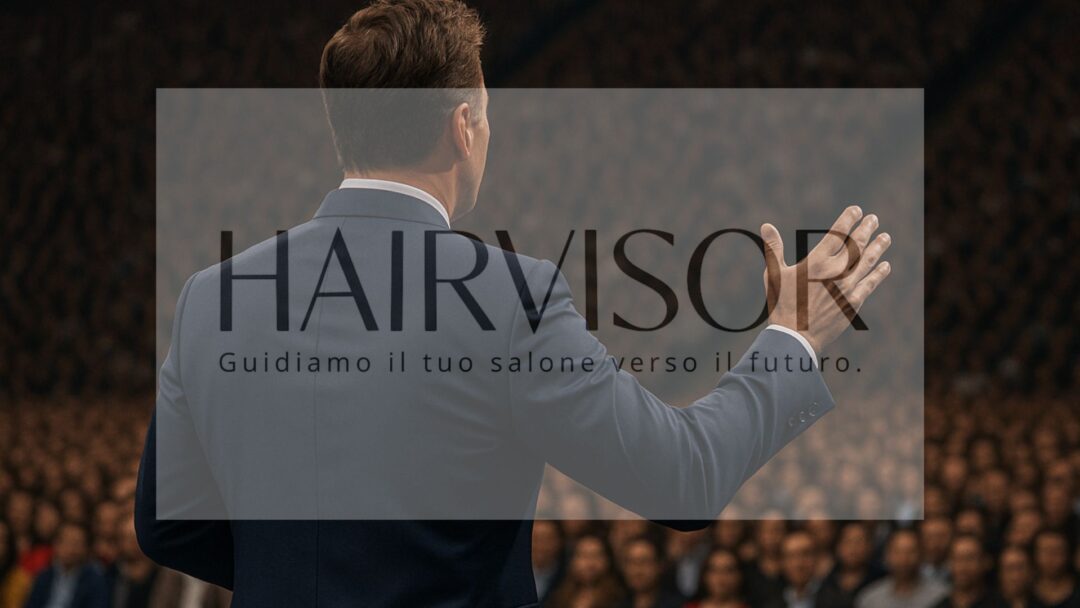 Coach di successo di spalle mentre parla davanti a una folla in una conferenza motivazionale, con logo HAIRVISOR in sovraimpressione.