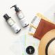 Travel kit Farmagan con shampoo e maschera in formato mini, affiancati da passaporto, biglietti aerei e fotocamera su sfondo chiaro.
