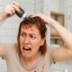 Donna disperata mentre si applica male il colore fai da te sui capelli nel bagno di casa.