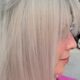 Primo piano laterale di capelli biondo perla lisci e luminosi su donna con frangia, realizzati in salone