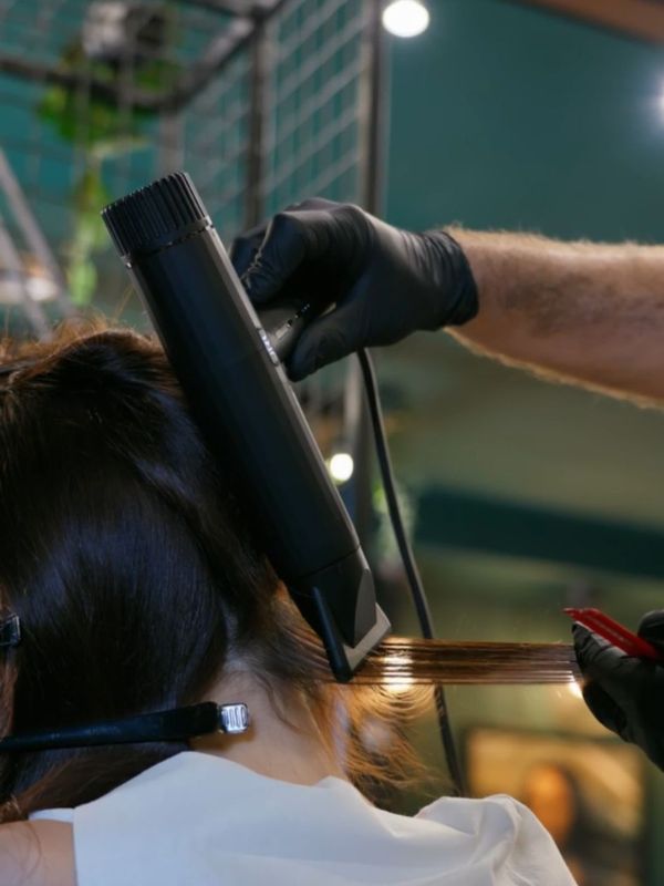 Stylist utilizza phon professionale JRL per asciugare e modellare i capelli di una cliente in salone