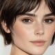 Taglio corto a scodella con frangia sfilata su capelli castani, look naturale e minimal, trend estate 2025.
