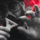 Hair stylist mostra accessorio JRL Professional in primo piano, con sfondo rosso sfocato