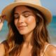 Donna con capelli luminosi e cappello in spiaggia, simbolo di protezione solare per i capelli in estate