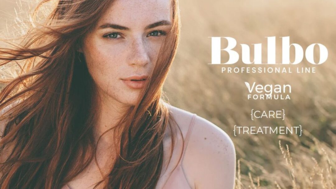 Donna dai capelli lunghi e rossi in un campo al tramonto, immagine promozionale della linea Bulbo Professional di Farmagan con formula vegan