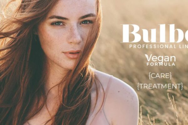 Donna dai capelli lunghi e rossi in un campo al tramonto, immagine promozionale della linea Bulbo Professional di Farmagan con formula vegan