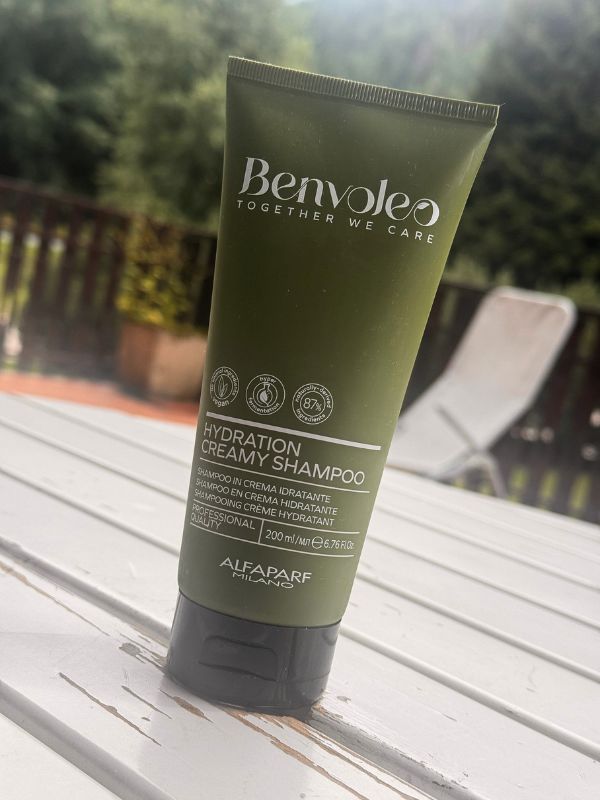 Shampoo Benvoleo Hydration Creamy di Alfaparf Milano appoggiato su un tavolo all’esterno, con sfondo naturale e sedia sfocata.