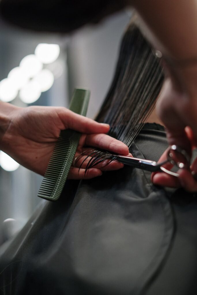 Parrucchiere che taglia con precisione capelli lisci con forbici professionali e pettine verde