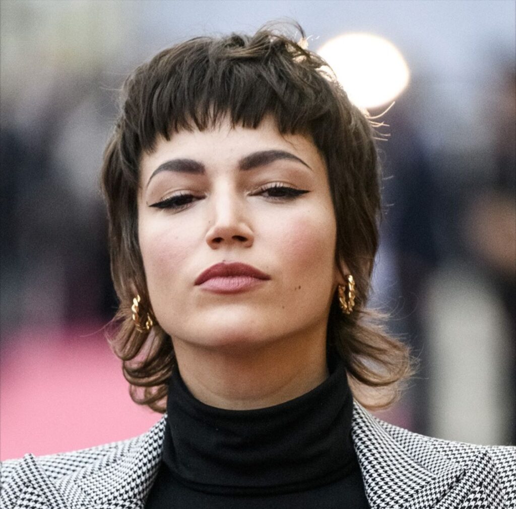 Donna con taglio Mixie corto scalato, frangia micro e styling spettinato effetto rock.