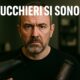 Parrucchiere di mezza età in salone, con espressione seria, tiene in mano un phon e una spazzola termica