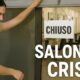 Parrucchiera chiude il salone con cartello "Chiuso" davanti a locali vuoti