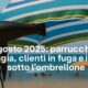 Parrucchiere in spiaggia che si rilassa al sole durante Ferragosto 2025, con un phon appoggiato sull’asciugamano.