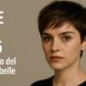 Modella giovane con Pixie Cut corto ribelle 2025, capelli castano scuro, sguardo deciso su fondo beige con scritta editoriale.