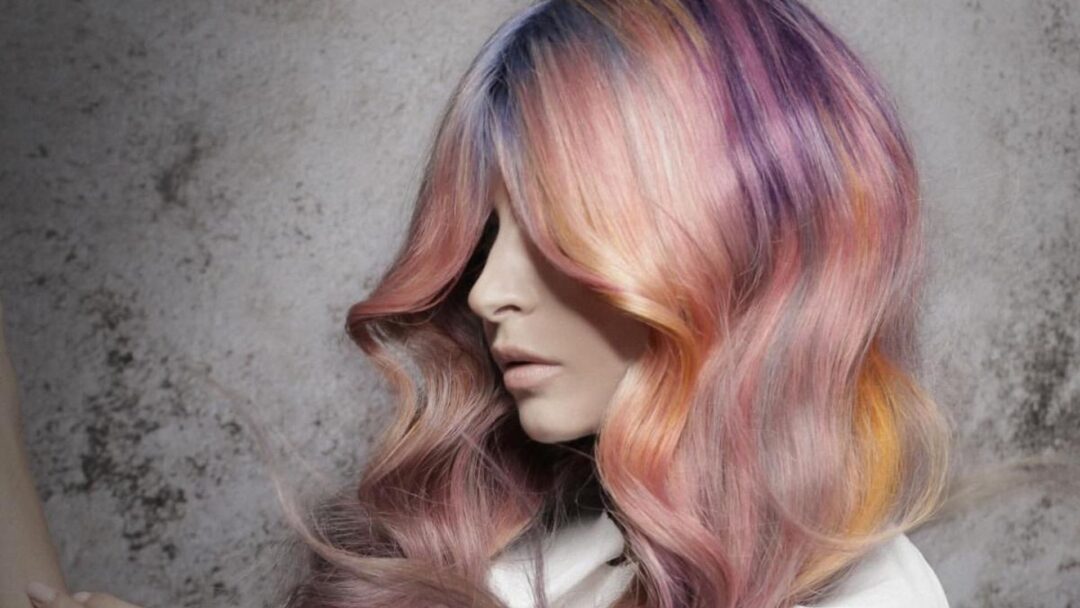 Capelli lunghi ondulati con sfumature rosa, viola, arancio e giallo, realizzati da Stefano Bugada per il progetto OVERLAPS di Hairtium.