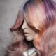 Capelli lunghi ondulati con sfumature rosa, viola, arancio e giallo, realizzati da Stefano Bugada per il progetto OVERLAPS di Hairtium.