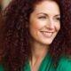 Donna Over 40 con capelli ricci naturali rossi, sorriso luminoso e look curato, simbolo di ricci definiti e sani.