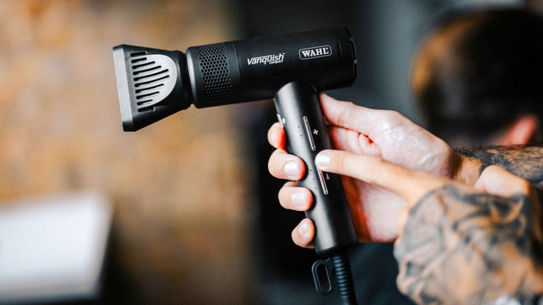 Asciugacapelli professionale Wahl Vanquish Compact tenuto in mano da un parrucchiere durante l’utilizzo in salone.