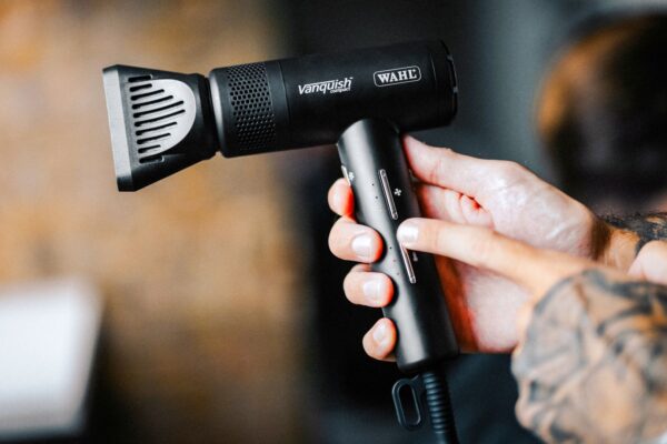 Asciugacapelli professionale Wahl Vanquish Compact tenuto in mano da un parrucchiere durante l’utilizzo in salone.