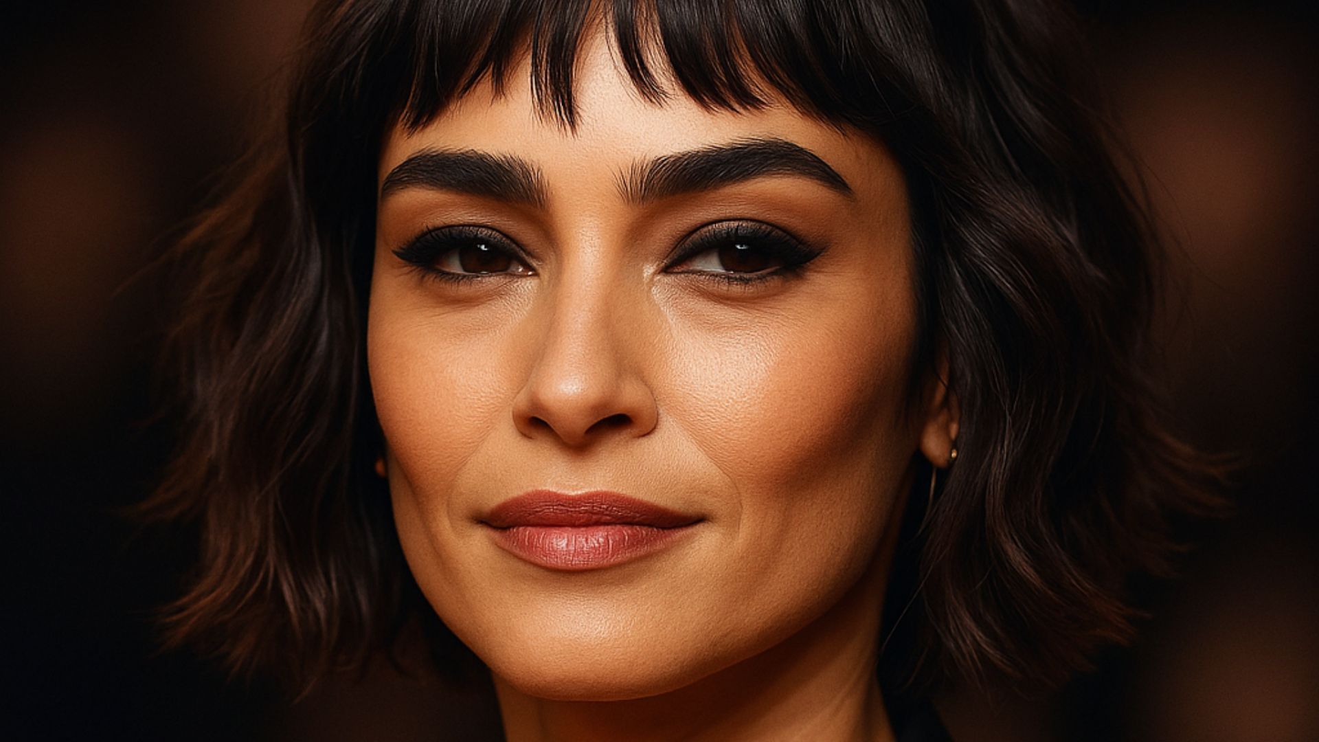 Donna con taglio corto sfilato e frangia irregolare, capelli castano scuro con onde leggere e naturali, trucco occhi intenso, look elegante e moderno, ispirazione Ghost Waves.