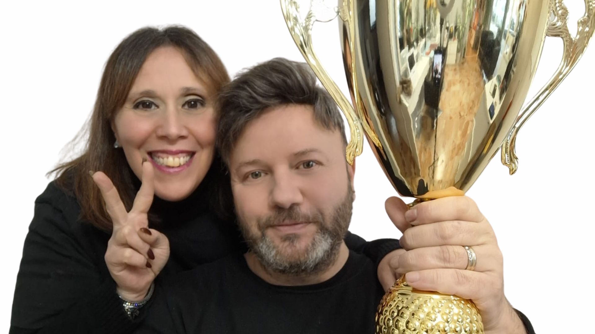 Un uomo e una donna sorridenti, rappresentanti di Maison Miracle, festeggiano un traguardo tenendo in mano un grande trofeo dorato.