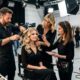 Parrucchiere, truccatrice e stylist che preparano il total look di una modella in uno studio televisivo davanti alle telecamere.
