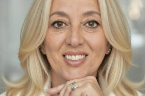 Primo piano professionale di Paola D'andria, sorridente con la mano sotto il mento.