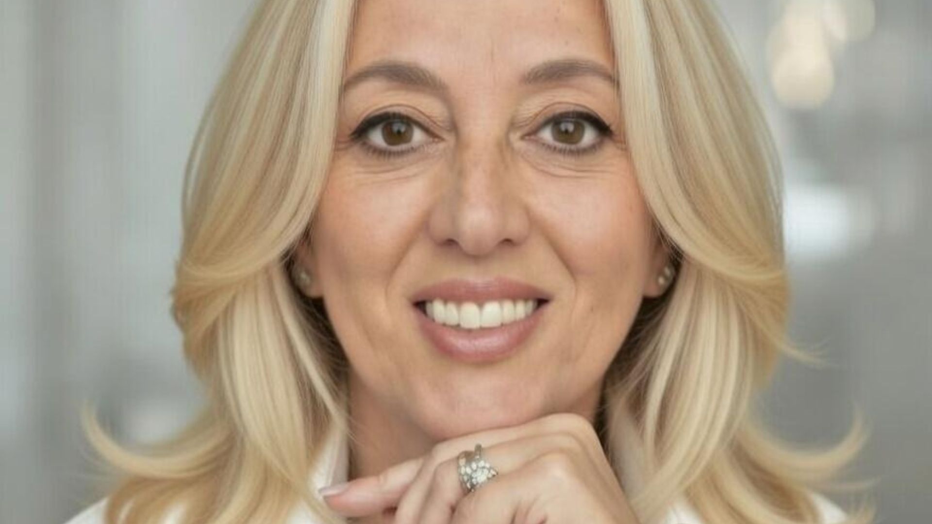 Primo piano professionale di Paola D'andria, sorridente con la mano sotto il mento.