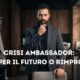 Un uomo barbuto e pensoso in giacca grigia e camicia nera all'interno di un moderno salone di parrucchiere. Un testo sovrapposto grande e bianco al centro recita: "CRISI AMBASSADOR: AIUTO PER IL FUTURO O RIMPROVERO?".