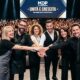 Un gruppo di sei parrucchieri e leader del settore hair & beauty unisce le mani sul palco principale del MDP Congress in un gesto di unità. Sullo sfondo, un grande schermo a LED mostra il testo "- UNITÀ E CRESCITA -" e un auditorium immenso e gremito di migliaia di colleghi applaude e scatta foto.