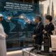 Stand fieristico di cosmetica B2B a Beautyworld Middle East 2026 a Dubai, con manager internazionali che analizzano la mappa delle rotte commerciali del mercato globale dei prodotti per capelli su un grande schermo digitale.