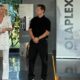 La formatrice Francesca Ventura in abito bianco presenta un foglio tecnico durante un seminario Olaplex in collaborazione con Academy Calenda, affiancata da un collega in abito nero.