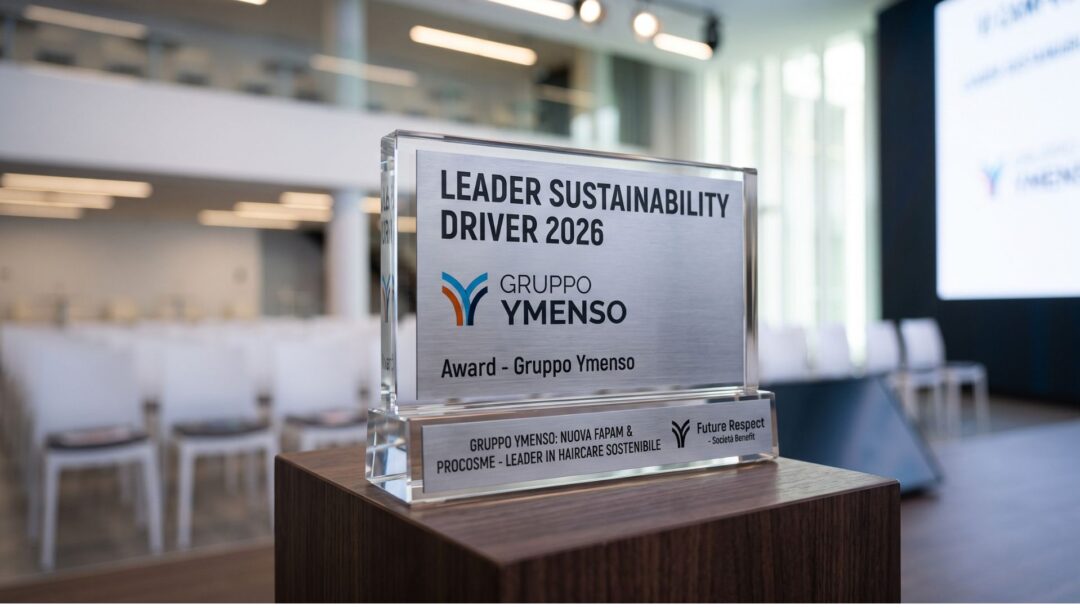 Trofeo in vetro e metallo del premio Leader Sustainability Driver 2026 assegnato al Gruppo Ymenso, posizionato su un piedistallo in legno con una sala conferenze sfocata sullo sfondo.