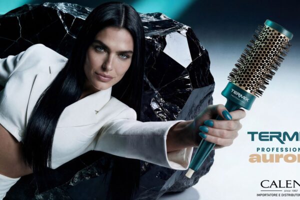 Modella con capelli lisci scuri regge una spazzola termica Termix Aurora Professional con manico verde acqua e setole dorate, sfondo scuro con roccia effetto specchio, logo Calenda importatore ufficiale