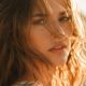 Modella con capelli al vento sotto il sole estivo, effetto luce sulla cuticola